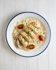 Baked chicken with thyme aroma on white rice. Top view table with decoration.