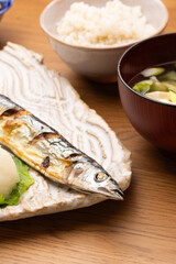 木製のテーブルに置かれた焼きサンマ