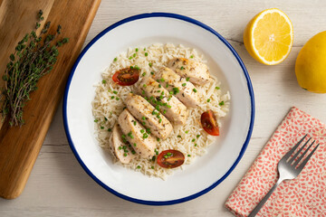 Baked chicken with thyme aroma on white rice. Top view table with decoration.