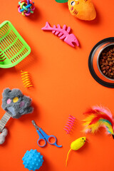 Frame of cat accessories and food on orange background. Flat lay, top view.