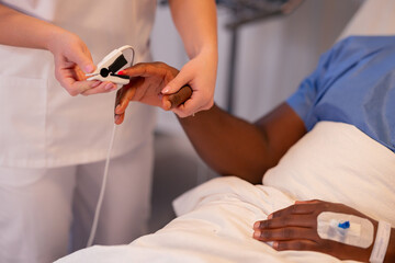 Female physician checks the African patient's blood oxygen using an oximeter in the hospital.
