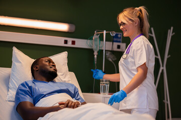 Standing next to the patient, the young doctor checks and adjusts the IV catheter.