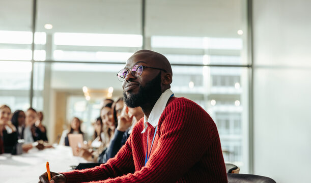 African American businessman attentively listening during a group conference in a modern office setting