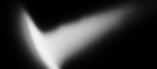 A abstract black and white image showcasing a gradient of light forming a soft, subtle shape against a dark background.