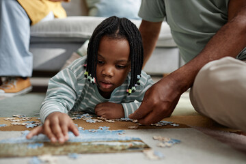 Young child laying pieces of puzzle on table with assistance from parent, creating an educational...