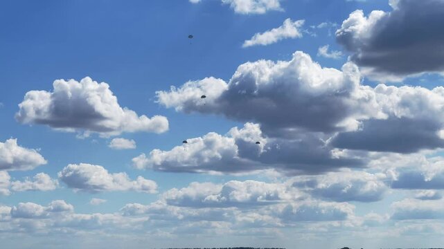 Parachutists descend from a cloudy sky