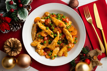 Sautéed chicken strips with vegetables and tomato sauce. Top view table with Christmas decoration.