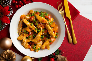 Sautéed chicken strips with vegetables and tomato sauce. Top view table with Christmas decoration.