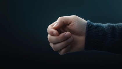 A tightly clenched fist symbolizing determination or frustration against a dark background.