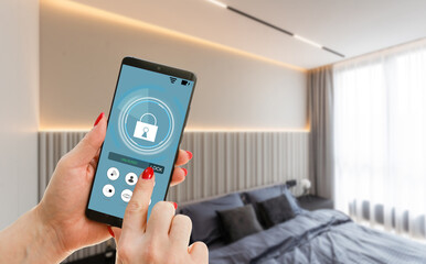 Young woman holding smart phone with launched security application at home. Concept of controlling and managing home security from a mobile device