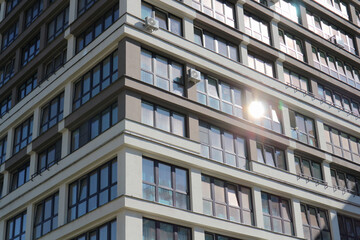 Windows of a multi-story modern residential building and a glare of sunlight.