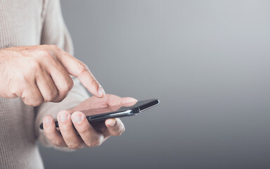 Person casually holding a smartphone, engaging with the touch screen in a subtle motion. Grey...
