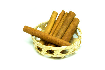 Group of cinnamon sticks in wooden basket isolated on white background closed up.