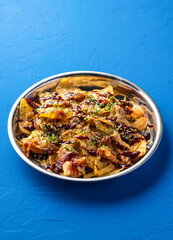Loaded Fries Nachos with Kimchi, Chicken, Cheese, Sauce, sesame seeds and green onion served in plate isolated on blue background closeup side view of fast food