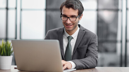 Fototapeta premium Smiling business man working on laptop at office.