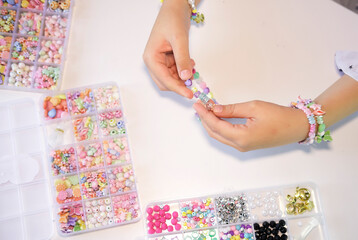 Making handmade beaded jewelry in workplace. Fashion, creativity, bracelets with beads and stones. Handmade jewelry, small business, hobby concept.