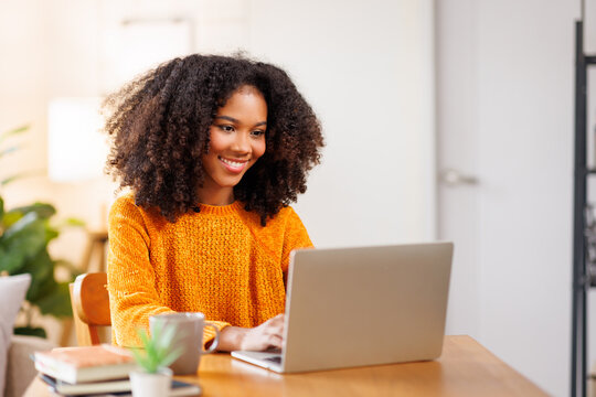 African American in Afro hair or girl using laptop computer learning distantly online sitting at desk at home. web education and E-learning
