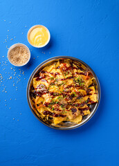 Loaded Fries Nachos with Kimchi, Chicken, Cheese, Sauce, Mayonnaise dip, sesame seeds and green onion served in plate isolated on blue background top view of fast food