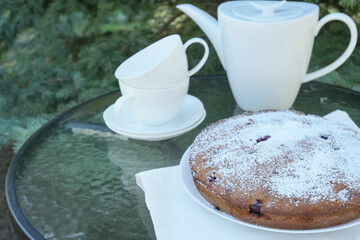 Homemade pie on  stand with napkin and teapot and cups with on a background. Side view. Space for text. 