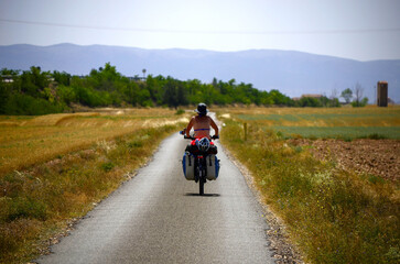 Obraz premium Woman traveling alone on a bicycle on roads and dirt roads surrounded by mountains and forests discovering natural environments. 