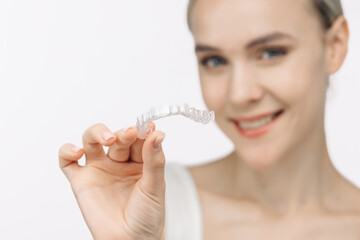 A woman with a beautiful smile and healthy teeth wears an orthodontic silicone trainer. This...