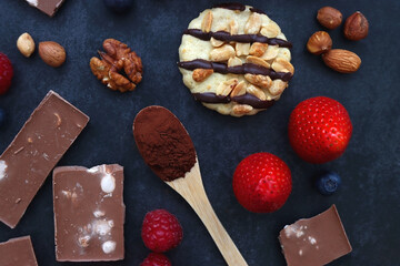 Macarons, chocolate, cookies, berries and various nuts on dark blue background. Top view.