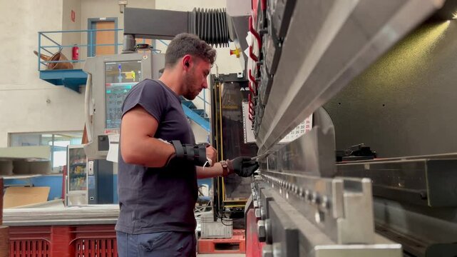 video of injured industrial worker operating metal bending machine with one hand in a factory