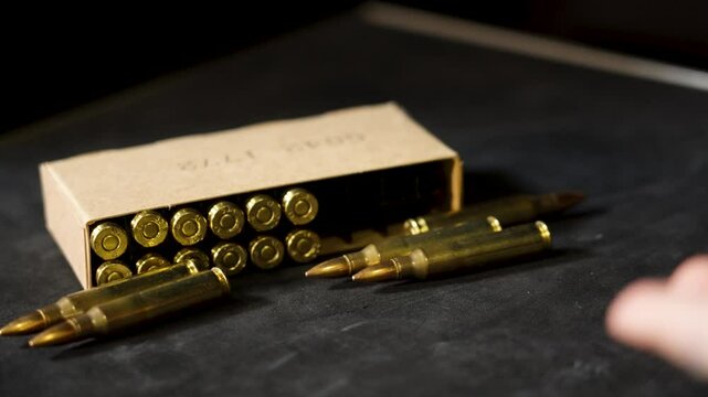 Ammunition rolls across frame to a pile near boxed rounds.