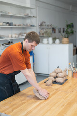 Potter kneads clay before using it in the workshop. Vertical photo. 