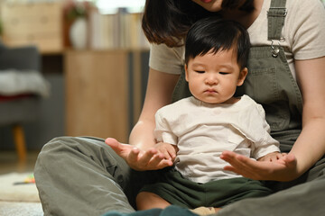 Loving young mother playing with little son on floor at home. Childhood and nurturing care concept