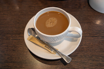 Coffee white cup and saucer served with teaspoon and demerara sugar packet