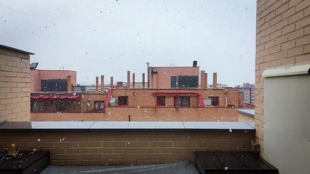 Nevando sobre las azoteas de edificios modernos. V&iacute;deo a c&aacute;mara lenta. Nieve cayendo en una tormenta de primavera en Madrid, Espa&ntilde;a. 27 03 2020.