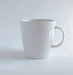 plain white ceramic mug with a simple handle. It has a clean and minimalistic design, perfect for enjoying coffee, tea, or any other hot beverage.