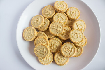 round cookies with various designs on them, including Christmas themed symbols like trees, snowmen, and other festive characters. vanilla or butter flavored sandwich cookies.