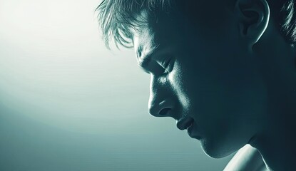 A contemplative close-up of a young male figure, captured in moody light, evoking emotions of introspection and vulnerability.