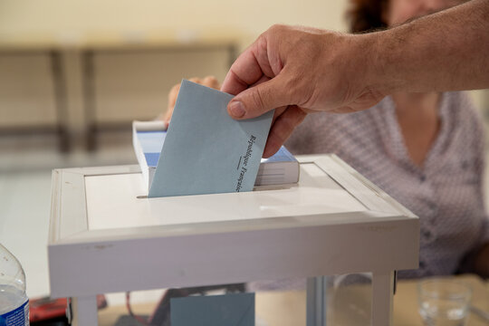 Vue d'une main d'un homme d&eacute;posant son bulletin de vote dans l'urne lors d'une &eacute;lection dans un bureau de vote en France.