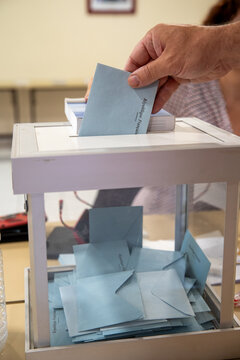 Vue d'une main d'un homme d&eacute;posant son bulletin de vote dans l'urne lors d'une &eacute;lection dans un bureau de vote en France.
