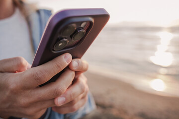  Close-Up of Hands Holding Smartphone at the Beach