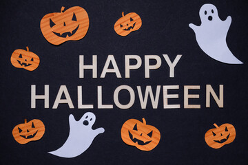 “Happy Halloween” inscription on black background with pumpkins and ghosts. Halloween holiday. For backgrounds and presentations