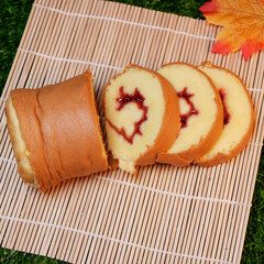 Sweet Rolled Cake Slices on Bamboo Mat with Maple Leaves, Fern and Foliage Decorations