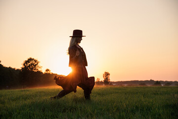 Carefree Woman in Field at Sunset Wearing Hat and Leather Jacket