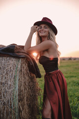 Woman in Maroon Hat and Flowing Skirt Posing in a Field