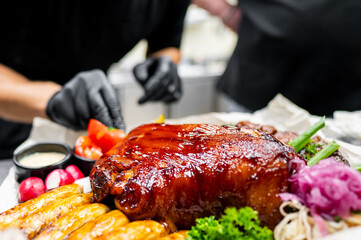 Close-up of a glazed roasted pork dish garnished with fresh vegetables and sauces on the side, presented on a white plate. Ideal for culinary, food photography, and restaurant menu themes.