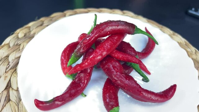 Red chili peppers rotating on a white plate