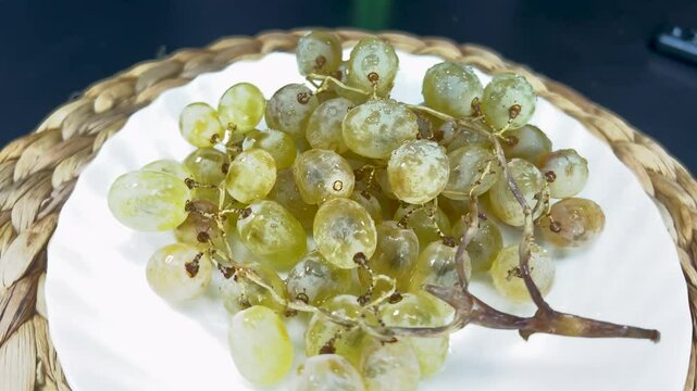 Rotating bunch of vibrant green grapes on a decorative plate