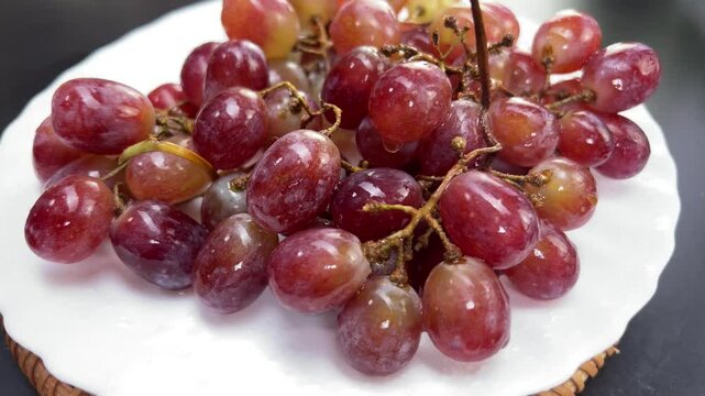 Rotating bunch of vibrant red grapes on a decorative plate
