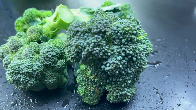 Fresh broccoli rotating on wet slate surface