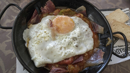 Revuelto de jamón , pisto de verduras y huevo frito servido en cazuela
