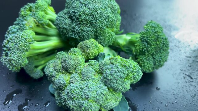 Fresh broccoli rotating on wet slate surface