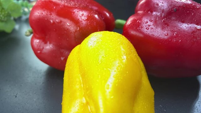 Red and yellow bell peppers rotating on black background